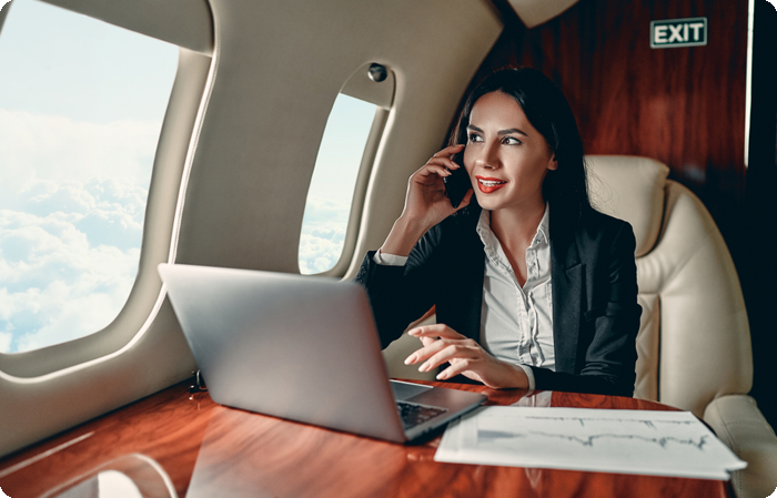 Business woman working while flying on private jet charter.